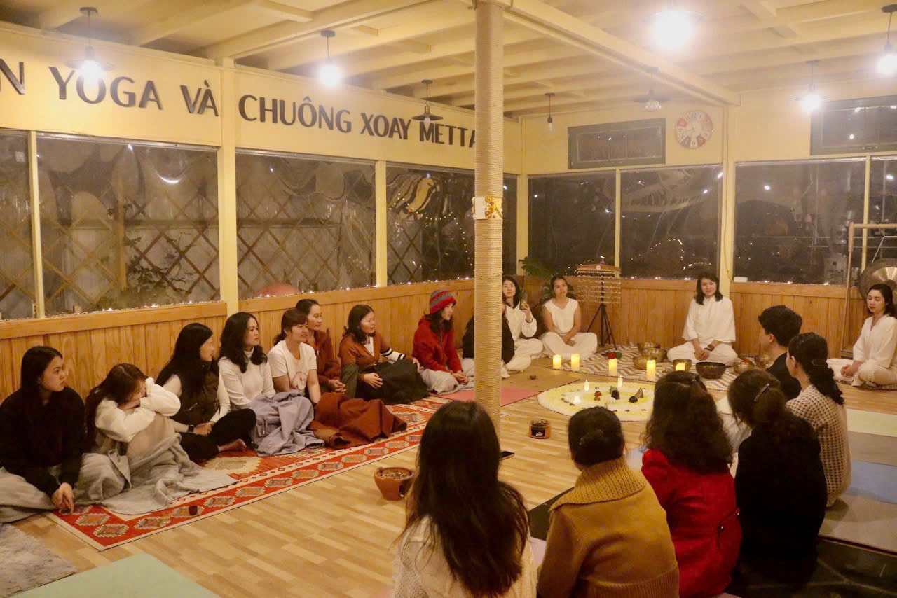 Nhóm 3-4 người ngồi trên thảm yoga, ánh sáng tự nhiên